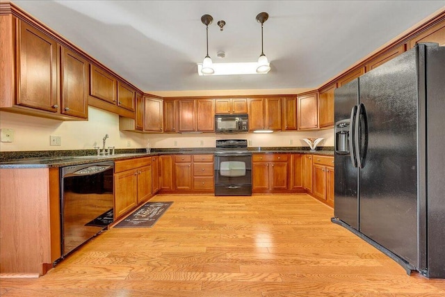 kitchen with decorative light fixtures, sink, black appliances, and light hardwood / wood-style flooring