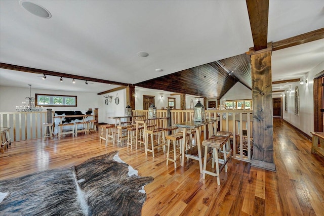 living room with light hardwood / wood-style floors, decorative columns, a chandelier, track lighting, and vaulted ceiling