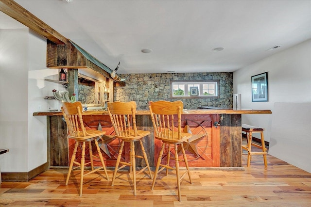 bar with baseboards, visible vents, light wood finished floors, and a dry bar