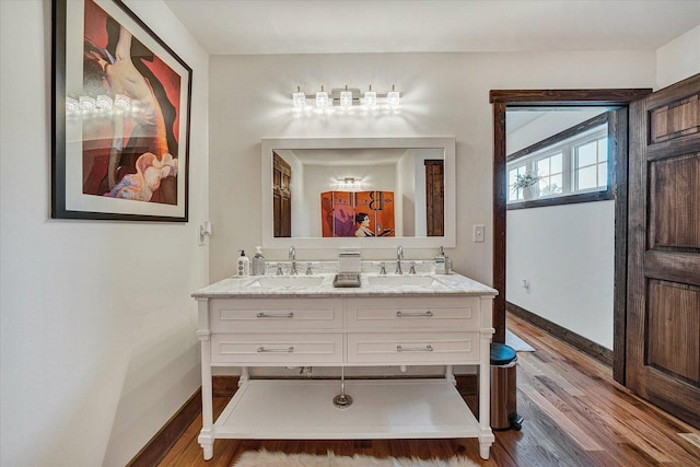 bathroom featuring wood-type flooring, oversized vanity, and dual sinks