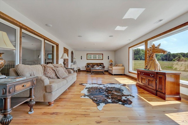 living room featuring light wood-type flooring and a skylight