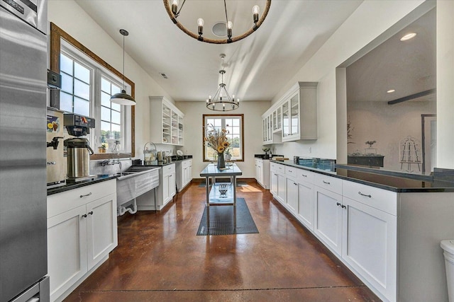 kitchen with dark countertops, white cabinetry, and glass insert cabinets