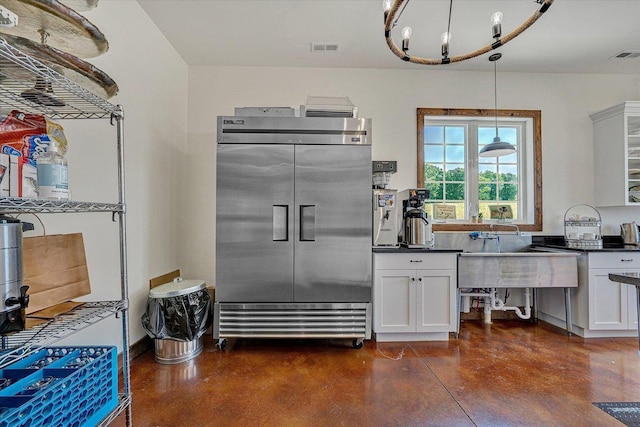 kitchen with dark countertops, finished concrete floors, white cabinetry, and built in fridge