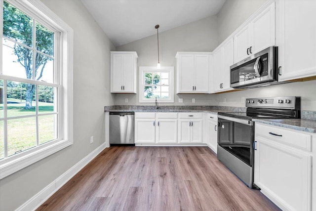 kitchen featuring appliances with stainless steel finishes, white cabinets, hanging light fixtures, and a sink