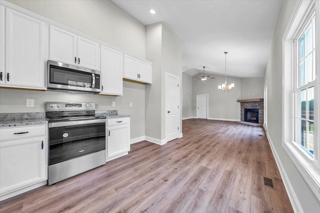 kitchen featuring stainless steel appliances, light wood-style floors, white cabinetry, and light stone countertops