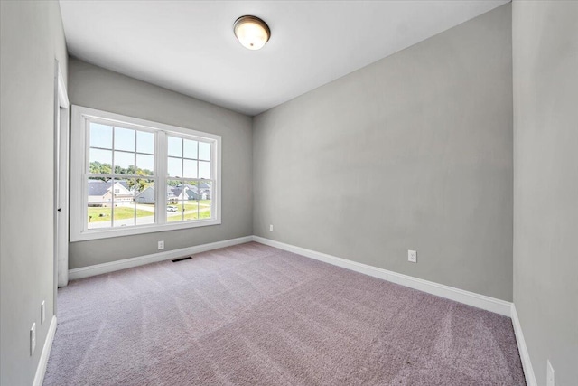 empty room featuring visible vents, baseboards, and light colored carpet