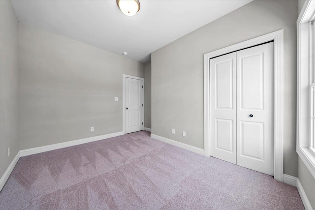 unfurnished bedroom with baseboards, a closet, and light colored carpet