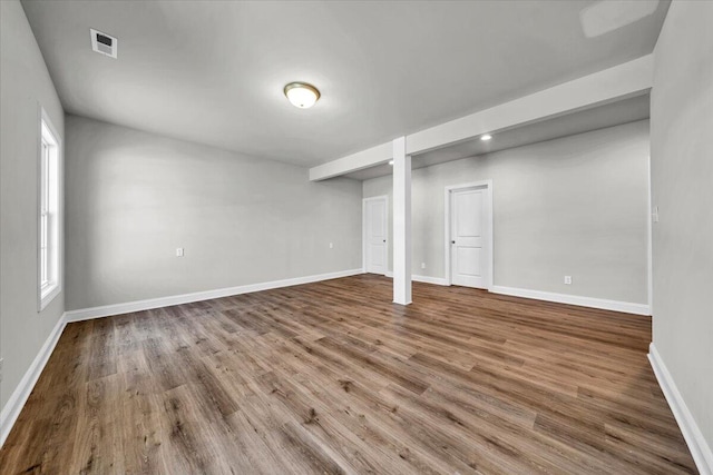 basement featuring baseboards, visible vents, and wood finished floors