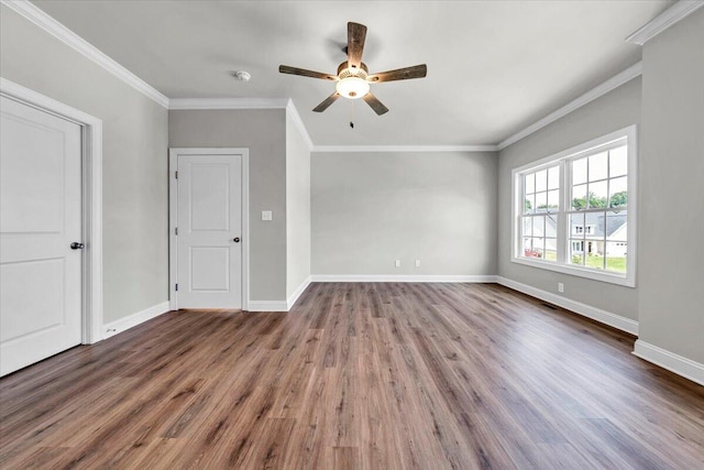 empty room with ornamental molding, wood finished floors, and baseboards