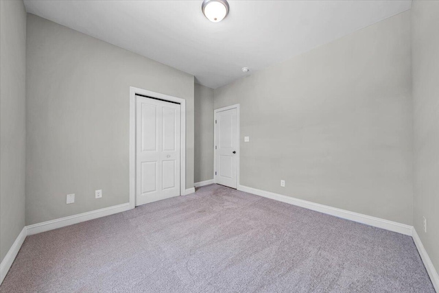 unfurnished bedroom featuring carpet floors, a closet, and baseboards