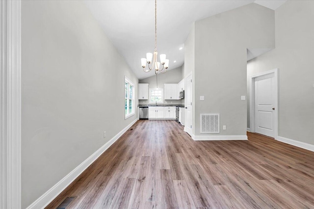 interior space with high vaulted ceiling, visible vents, baseboards, light wood finished floors, and an inviting chandelier