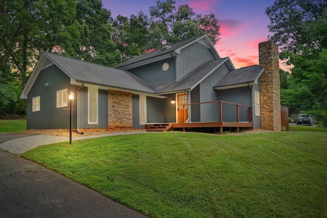 view of front of property featuring stone siding, a chimney, and a lawn