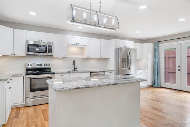 kitchen with appliances with stainless steel finishes, a sink, white cabinets, and a center island