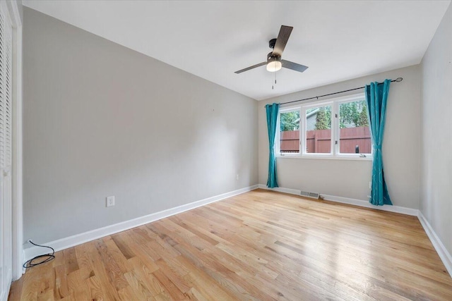 unfurnished room featuring light wood-style floors, visible vents, baseboards, and a ceiling fan