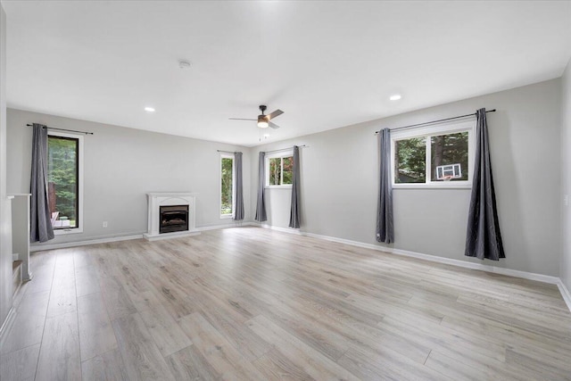 unfurnished living room featuring light wood-style flooring, recessed lighting, a high end fireplace, and baseboards