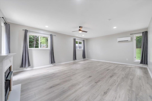 unfurnished living room featuring a wealth of natural light, light wood-style flooring, and a wall mounted AC