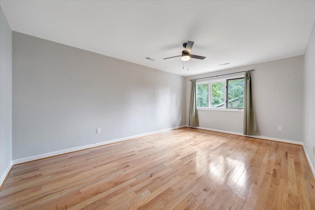 spare room with light wood finished floors, a ceiling fan, and baseboards