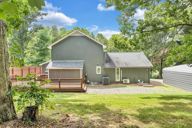 back of property with a shingled roof, fence, a deck, and a lawn