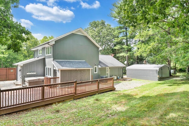 back of house featuring a deck, a shingled roof, a lawn, and a hot tub