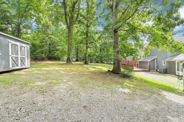 view of yard featuring an outbuilding, central air condition unit, and a shed