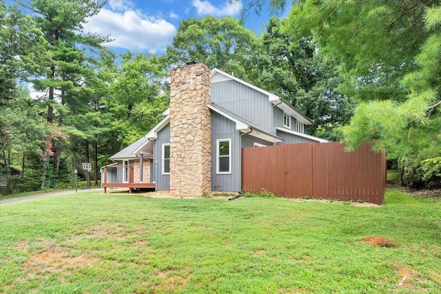 view of property exterior with a chimney, fence, and a lawn