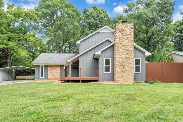 view of front of property with fence, roof with shingles, a carport, a chimney, and a front yard