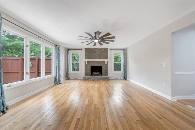 unfurnished living room with ceiling fan, light wood-type flooring, a fireplace, and baseboards