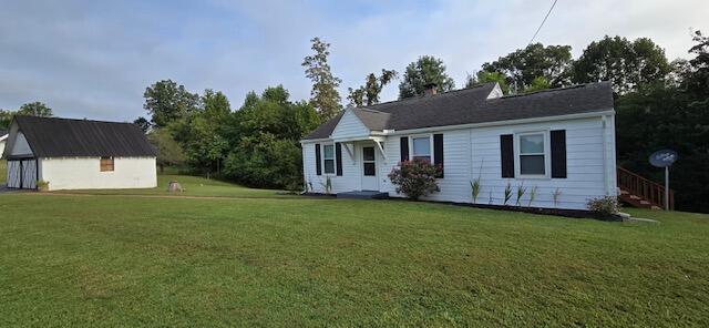 view of front of home featuring a front lawn and a storage shed