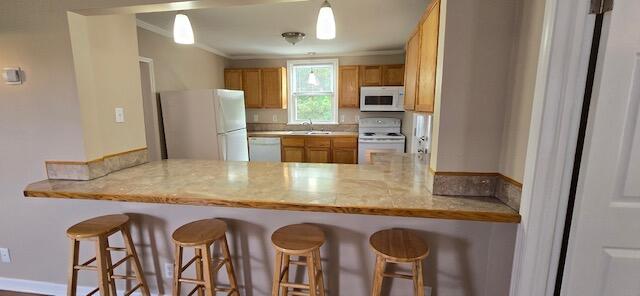 kitchen with white appliances, a kitchen breakfast bar, and kitchen peninsula