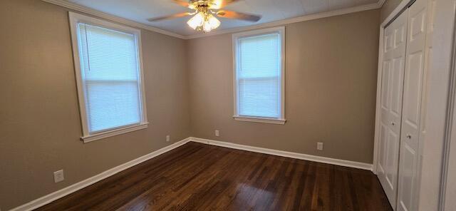 unfurnished bedroom featuring dark wood-type flooring, ceiling fan, ornamental molding, and a closet