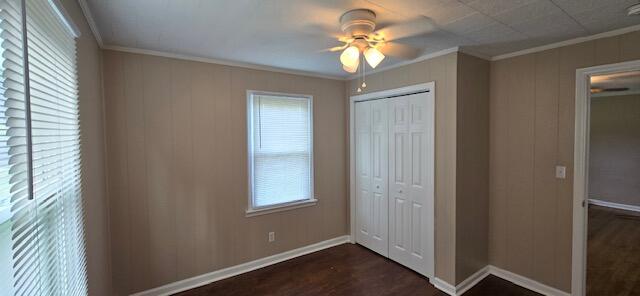 unfurnished bedroom with dark hardwood / wood-style floors, ceiling fan, ornamental molding, and a closet