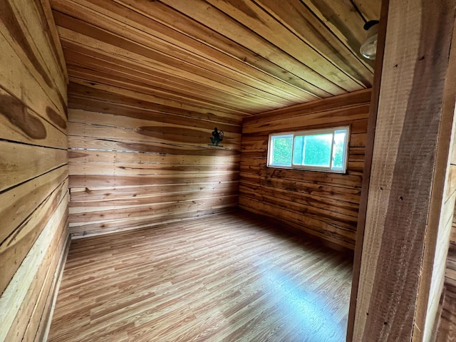 empty room featuring wooden walls, wooden ceiling, and light wood-type flooring