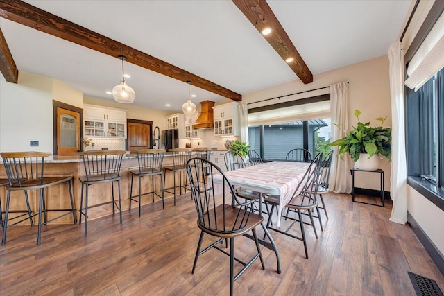 dining space featuring beam ceiling and dark wood-type flooring