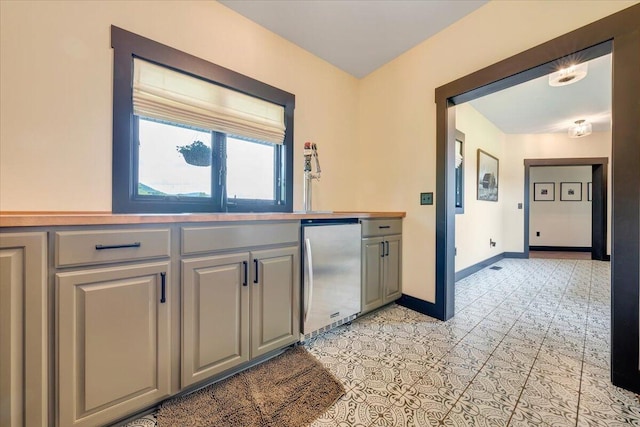 kitchen with gray cabinets, stainless steel fridge, and light tile patterned floors