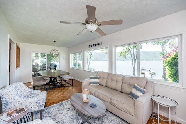 living room featuring a water view, parquet flooring, ceiling fan, and a textured ceiling