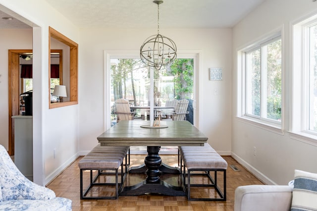 dining space featuring a notable chandelier, parquet flooring, and a textured ceiling