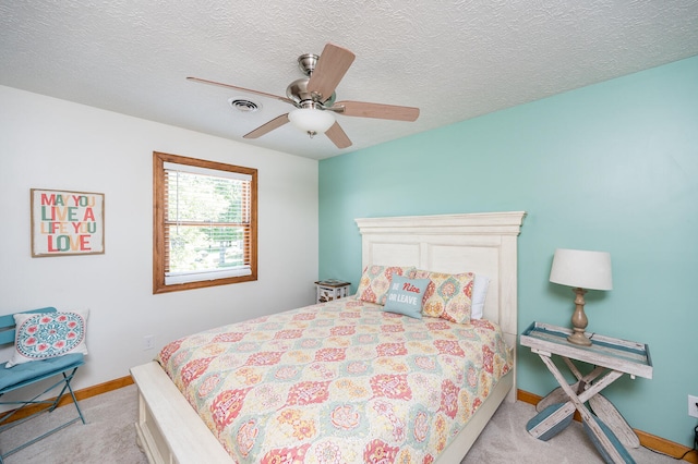 carpeted bedroom with ceiling fan and a textured ceiling