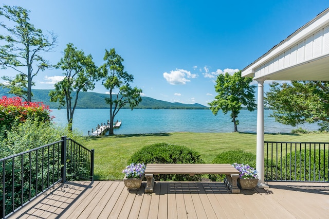 wooden terrace with a lawn and a water and mountain view