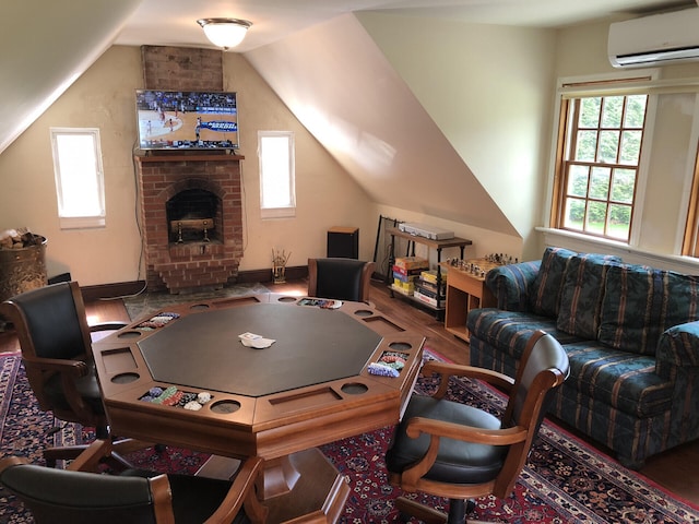 rec room featuring a fireplace, hardwood / wood-style floors, a wall mounted AC, and lofted ceiling