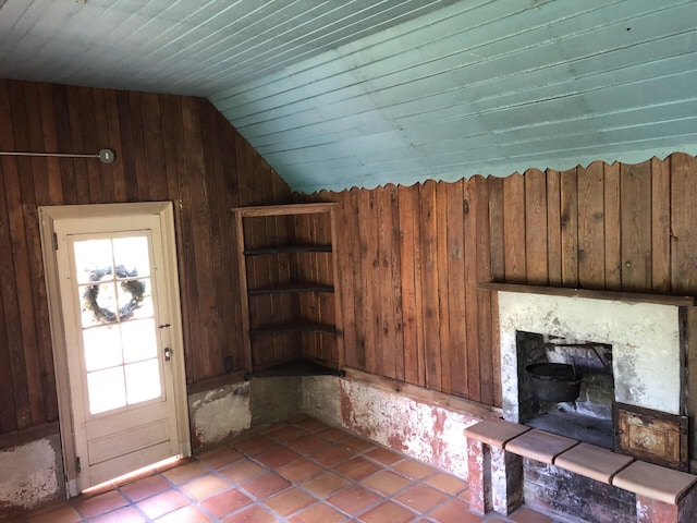 entrance foyer featuring light tile patterned floors, vaulted ceiling, and wooden walls