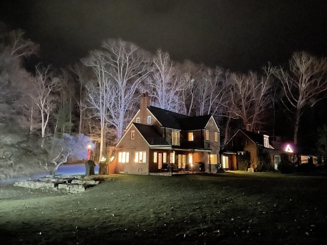 back house at night featuring a yard