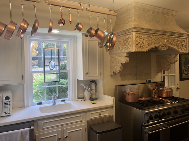 kitchen featuring white cabinets, dishwashing machine, sink, and stainless steel stove