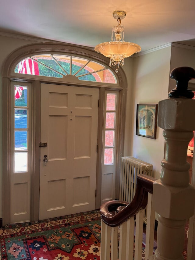 entrance foyer with radiator heating unit, a chandelier, and ornamental molding