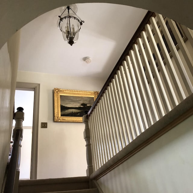 stairs featuring a notable chandelier