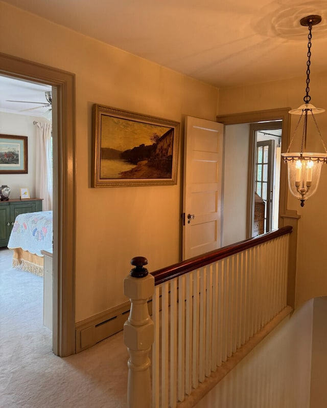 hallway featuring light carpet and a chandelier