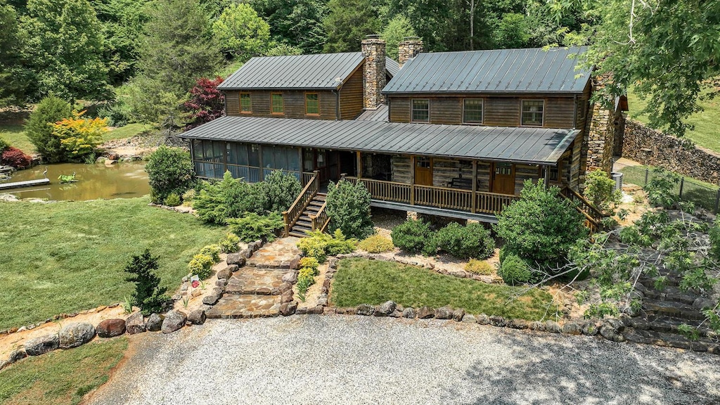 cabin featuring a sunroom, covered porch, and a front yard