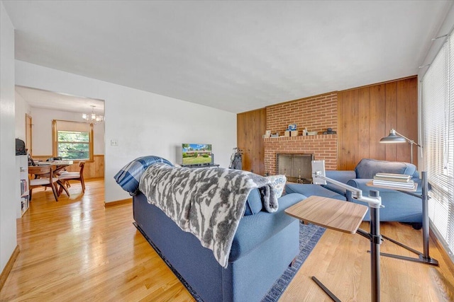 living room featuring hardwood / wood-style flooring, a fireplace, wooden walls, and an inviting chandelier