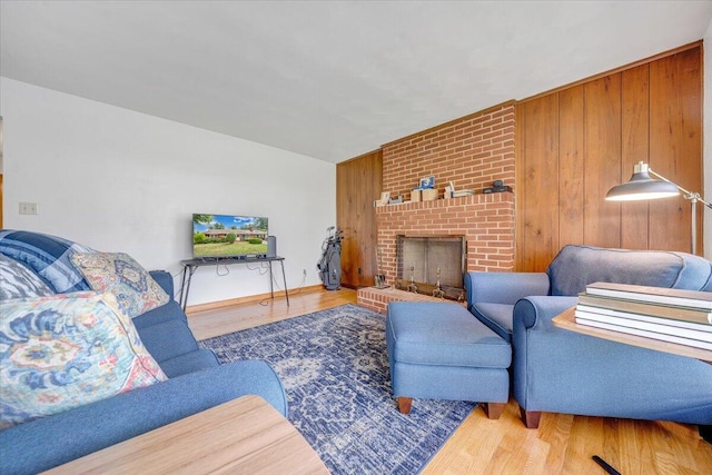 living room with hardwood / wood-style flooring, wooden walls, and a brick fireplace