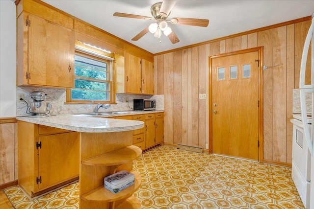 kitchen featuring sink, crown molding, kitchen peninsula, and wood walls