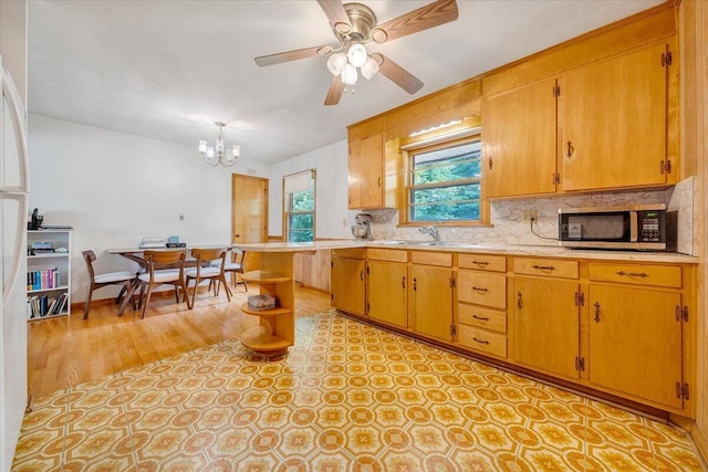 kitchen featuring sink, ceiling fan with notable chandelier, and decorative backsplash